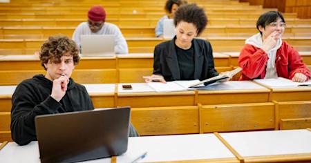 Students studying in a classroom and working on their laptops.