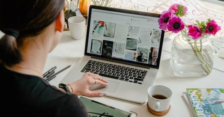 A graphic designer using a laptop and stylus tablet to create a design.