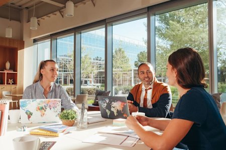 Co-workers sitting at a conference table in their office while working on their laptops.