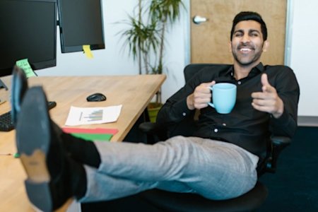 Man at desk with a smile, praising the benefits of hybrid work from home and office with Splashtop