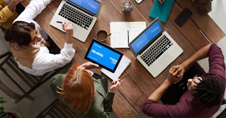 A group of coworkers using their devices at a conference table.