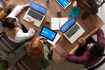 A group of coworkers using their devices at a conference table.