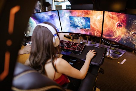 A person on a gaming computer with multiple displays.