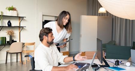 To workers looking at a computer screen on a desk.