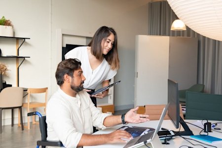 To workers looking at a computer screen on a desk.