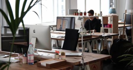A man working in an office with several desks and computers.