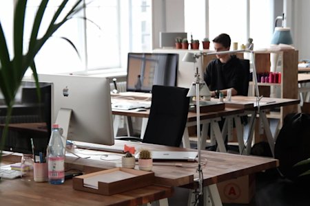 A man working in an office with several desks and computers.