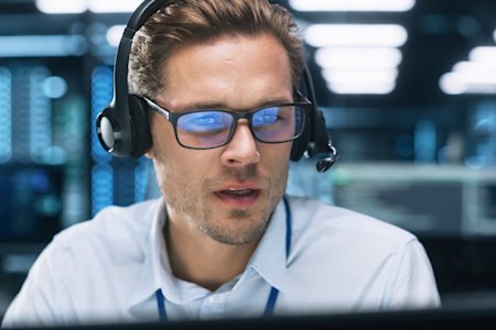 Male IT analyst examining remote desktop access on his laptop in datacenter