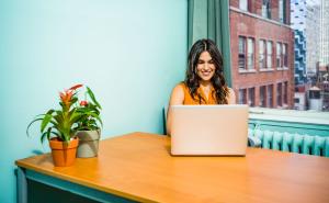 A happy woman sitting at a table using Splashtop on her laptop