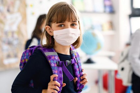 Young girl wearing a protective face mask while attending school as a precaution against Covid-19