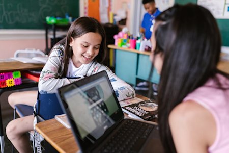 Students in a school classroom working on laptops.