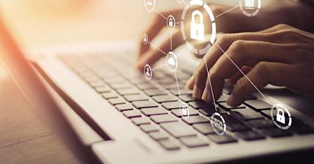 A hand typing on a laptop keyboard with security icons