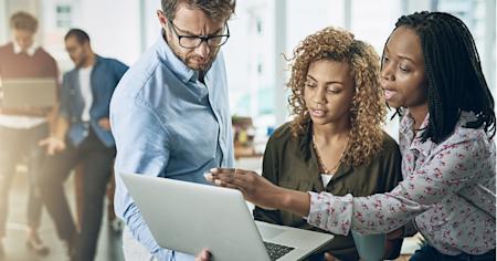 A group of professionals collaborating on a laptop, discussing IT incident response strategies in a modern office setting.