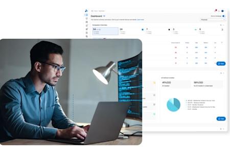 A man sits at a desk with multiple monitors displaying code and graphs, holding documents with charts; the top left shows a computer dashboard for device management and monitoring.