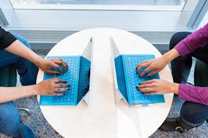 Two laptops being using on a table.