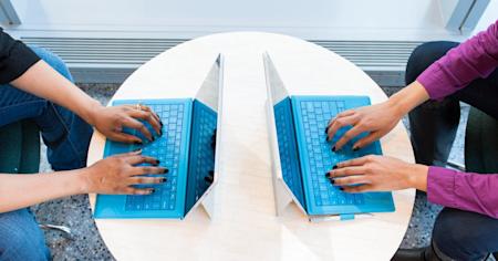 Two laptops being using on a table.