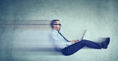 Man on a laptop with a big smile symbolizing that he's feeling a boost in speed or efficiency