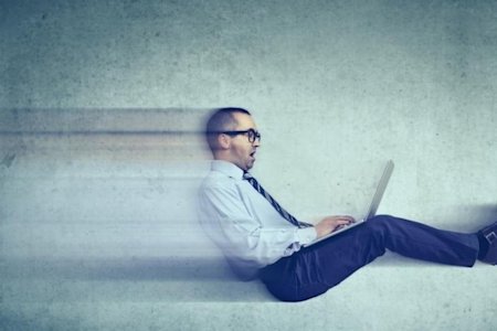 Man on a laptop with a big smile symbolizing that he's feeling a boost in speed or efficiency