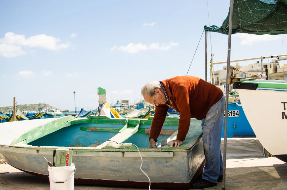 Surf Garage - Old man repairing a small boat