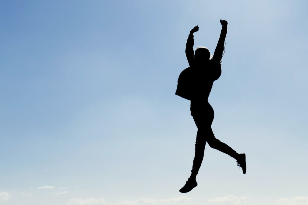 person jumping against blue sky