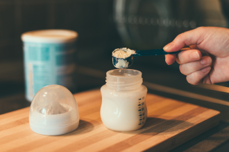 Scooping infant formula into baby bottle