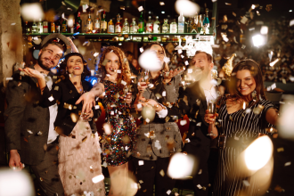 Group of happy people throwing confetti while enjoying party