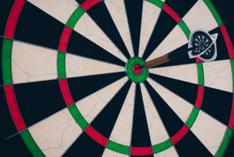 A dart hits a bullseye shot on a dartboard 