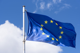 Eurozone EU flag flies in the wind standing before a blue sky with a large white cloud in the background screen bottom left 