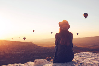 How To 15 - girl in a hat sits on a hill and looks at air balloons