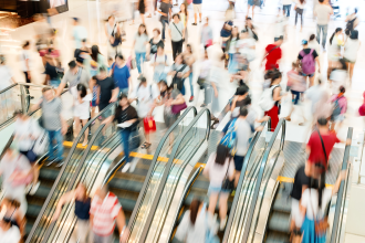 Blurry picture of a busy mall escalator with lots of shoppers