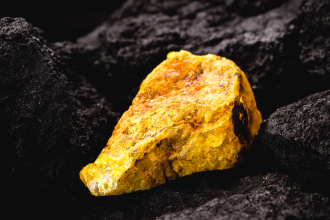 A hard-rock nugget of uranium ore is juxtaposed against a black background 