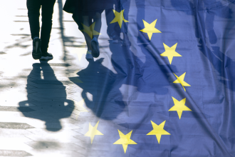 Two individuals walk alongside one another while the EU flag is superimposed over the right half of the image