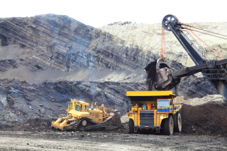 Two yellow mine vehicles at work in an open cut iron ore project at an unknown location 