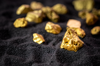 Gold nuggets sitting on dark sand