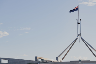 The Australian flag flies atop the flagpole and spire of Parliament House, Canberra