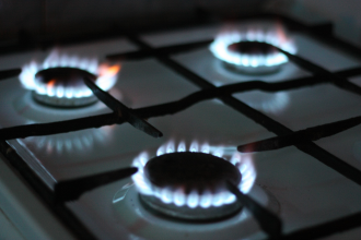 A residential gas burner stovetop firing in a dimly lit kitchen 