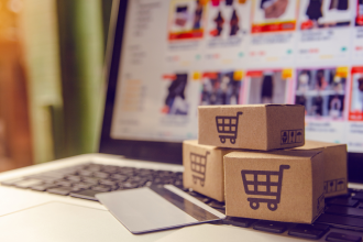 Three boxes with shopping cart logos in front of a macbook eCommerce