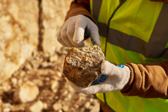 A technician holds a piece of ore with copper mineralisation present