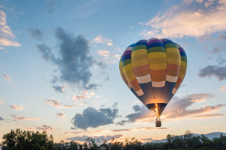 hot air balloon is flying at sunrise