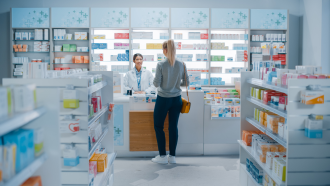 A customer retrieves a prescription from a mock-up pharmaceutical store for the purposes of an illustrative photograph