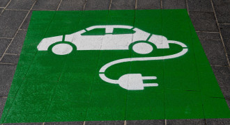 A floor painting in the style of carpark demarcation depicts a car with an electrical cable protruding out of the rear of a passenger vehicle 