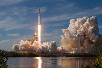 SpaceX rocket launching into space next to a lake