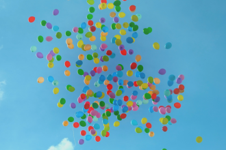 An array of differently coloured helium balloons are let loose into the sky 