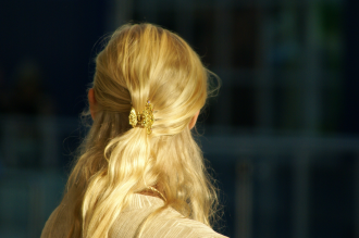 The back of a blonde woman-s head lit up in the sun in the style of Goldilocks