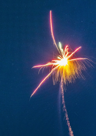 Fireworks explode in mid-air against an azure sky 