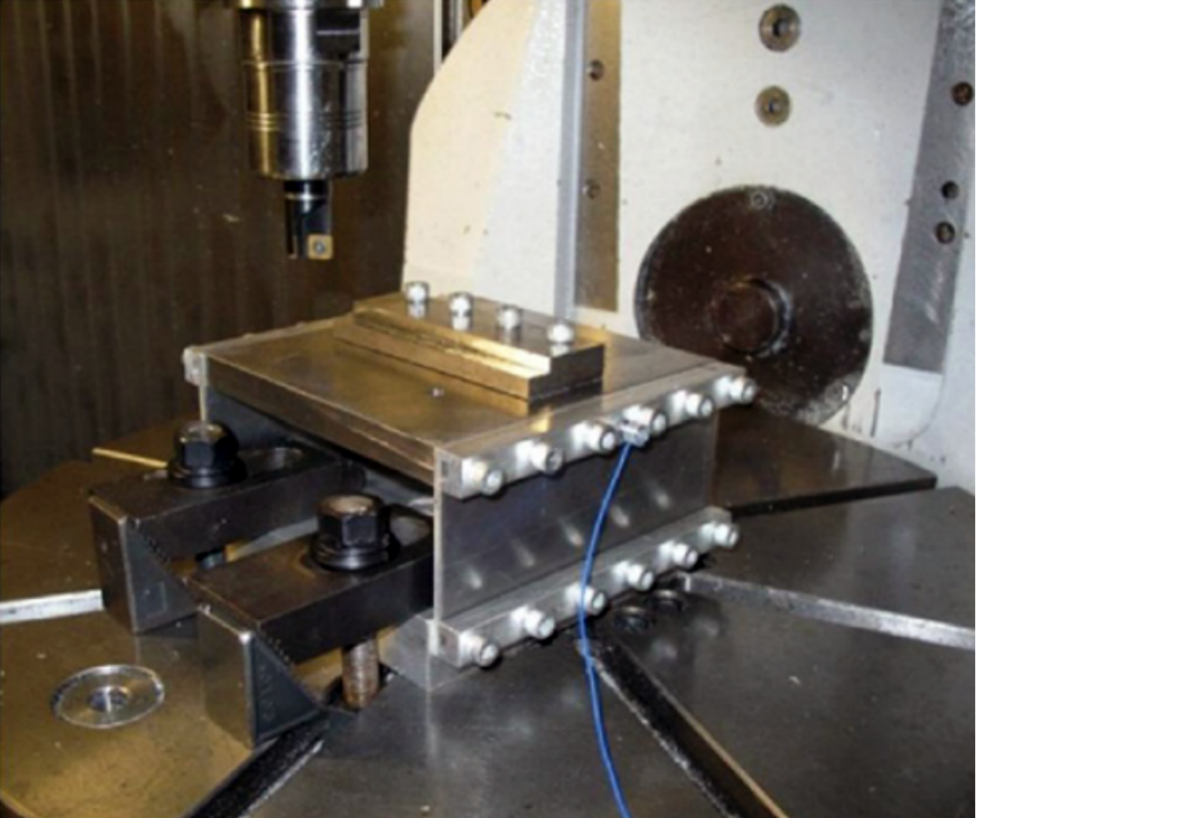 A photograph of the flexure-based milling setup used to machine an AISI 1018 steel workpiece.