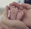 Pies de bebé entre las manos de su madre