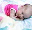 Bebé con vestido rosa acostada boca abajo