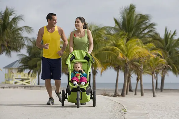 Pareja de padres con su hijo en coche caminando en la playa