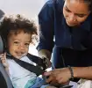 Mamá con su pequeño poniéndole silla de bebé para auto.